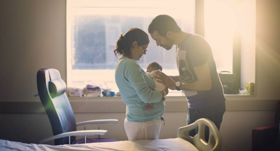 Dos padres miran a su recién nacido. 