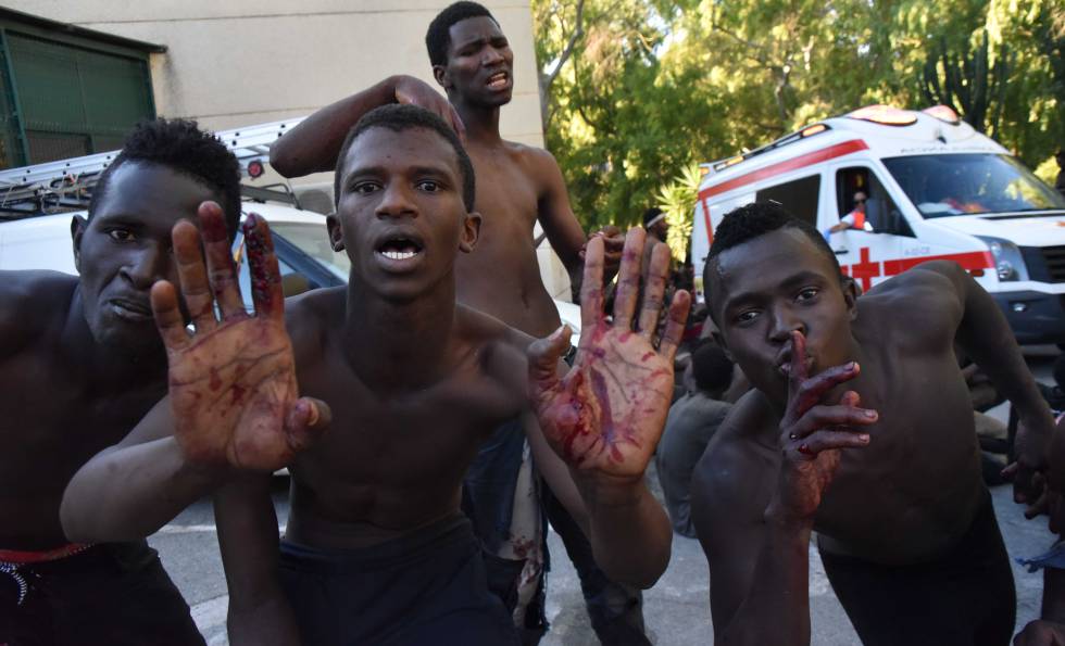 Varios inmigrantes, con las manos heridas por las concertinas de la valla.