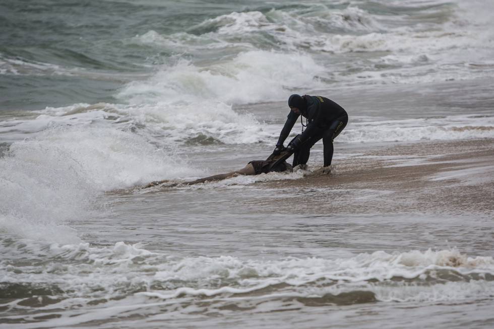Un agente de la Guardia Civil rescata el cadáver de un inmigrante el pasado jueves en una playa de Caños de Meca en Cádiz.