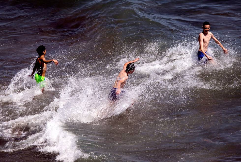 Unos jóvenes se bañan en la playa del Rincón de la Victoria (Málaga).