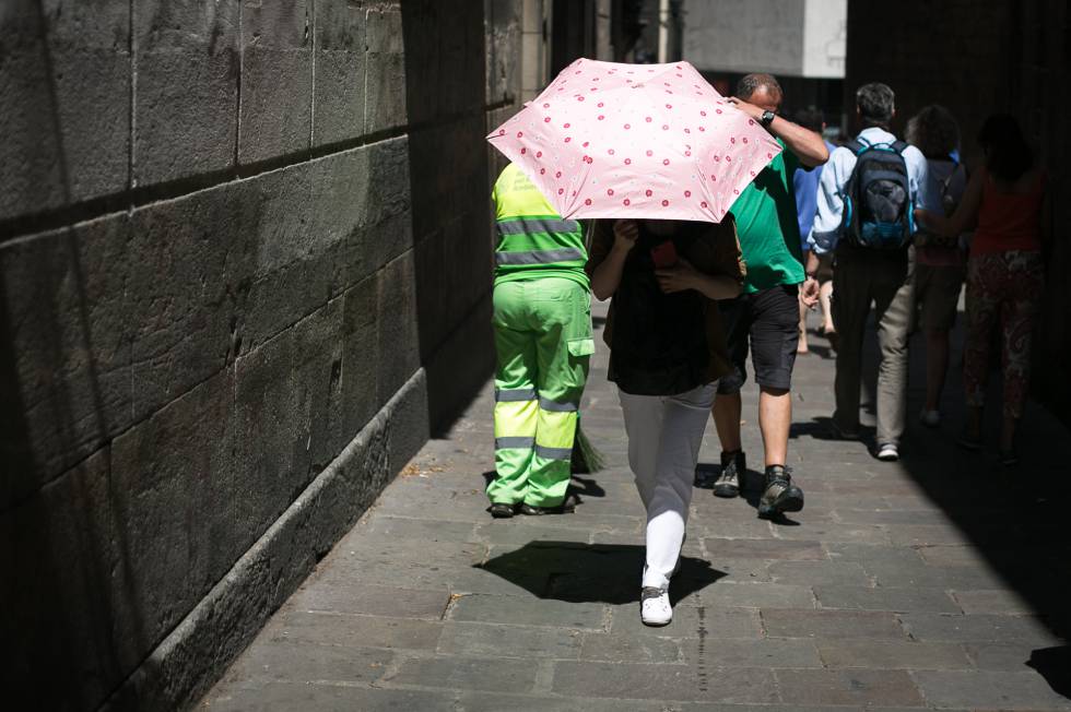 Turistas pasean bajo las altas temperaturas por el centro de Barcelona.
