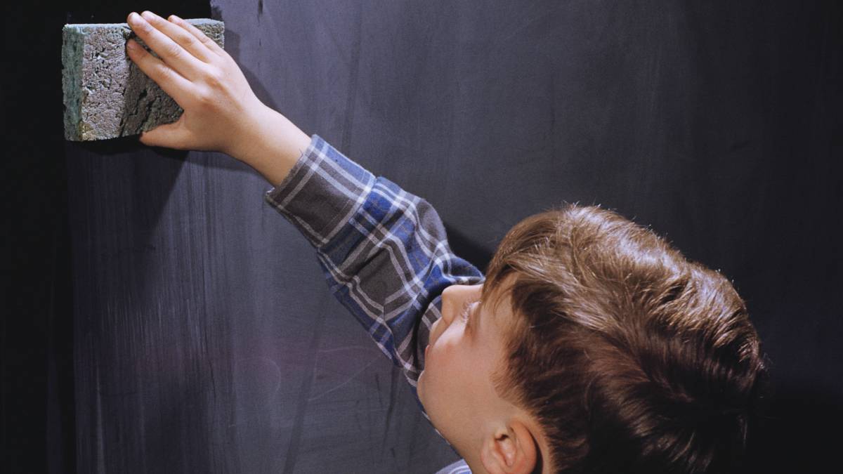 Un niño borra una pizarra.