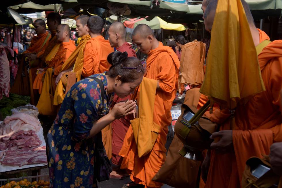 Una mujer frente a monjes budistas en Camboya.