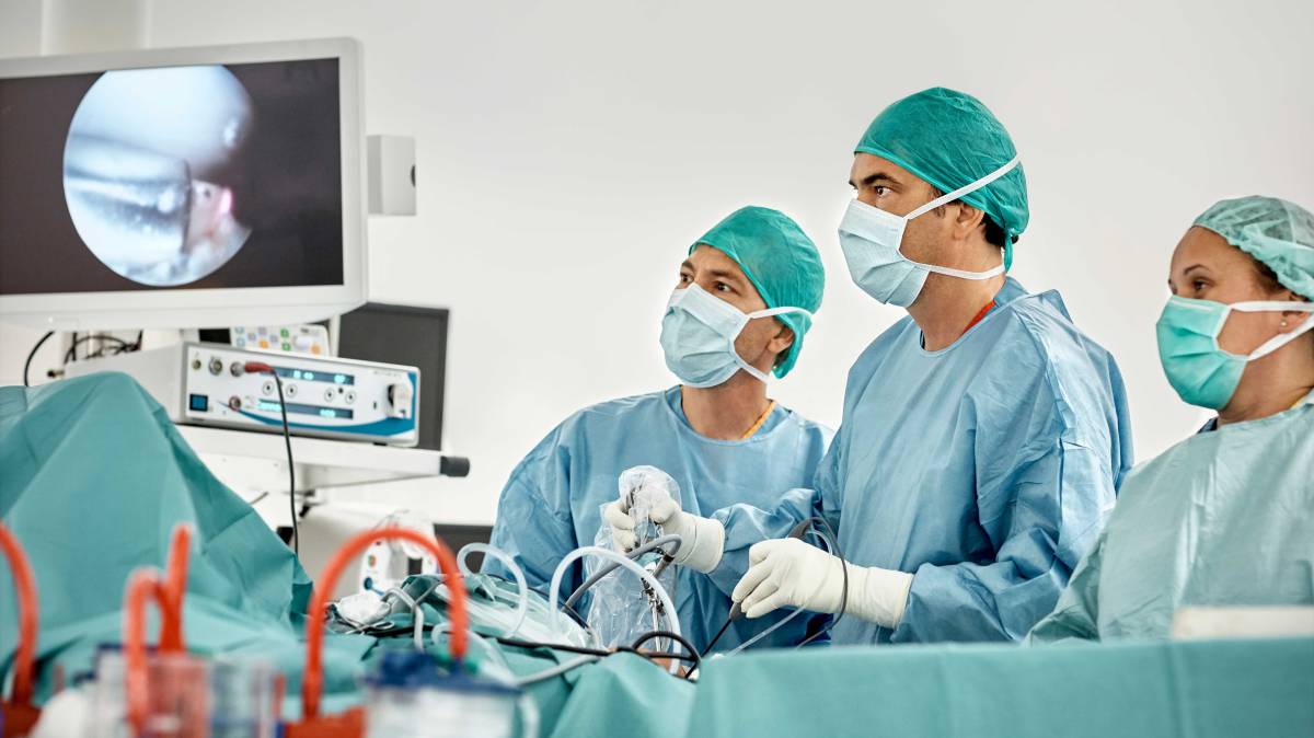 Cirujanos observan un monitor durante una intervención de rodilla. 