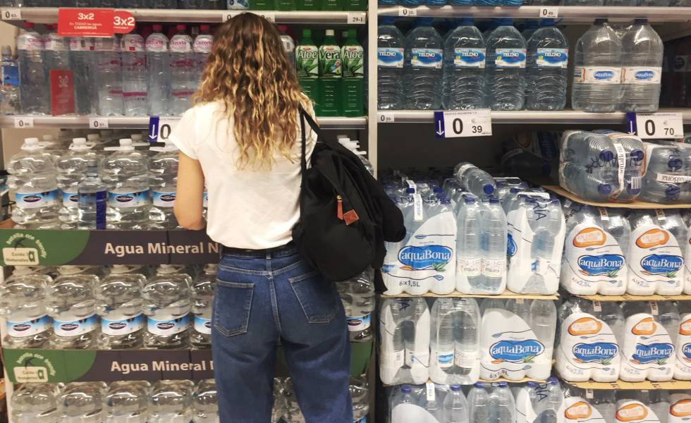 Una joven frente al estante de botellas de agua de plástico en un supermercado en Madrid.