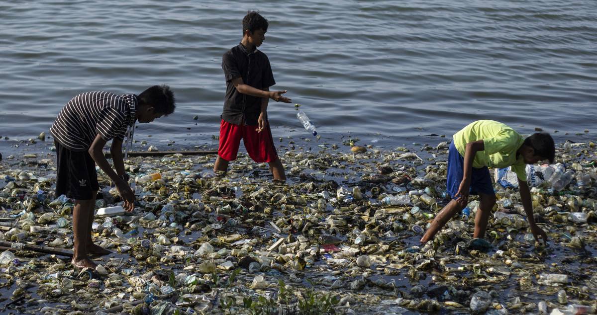 Niños buscan entre la basura en el agua en Indonesia. 