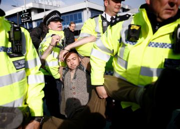 Varios policías detienen a un activista de Extinction Rebellion en el aeropuerto London City, este jueves.