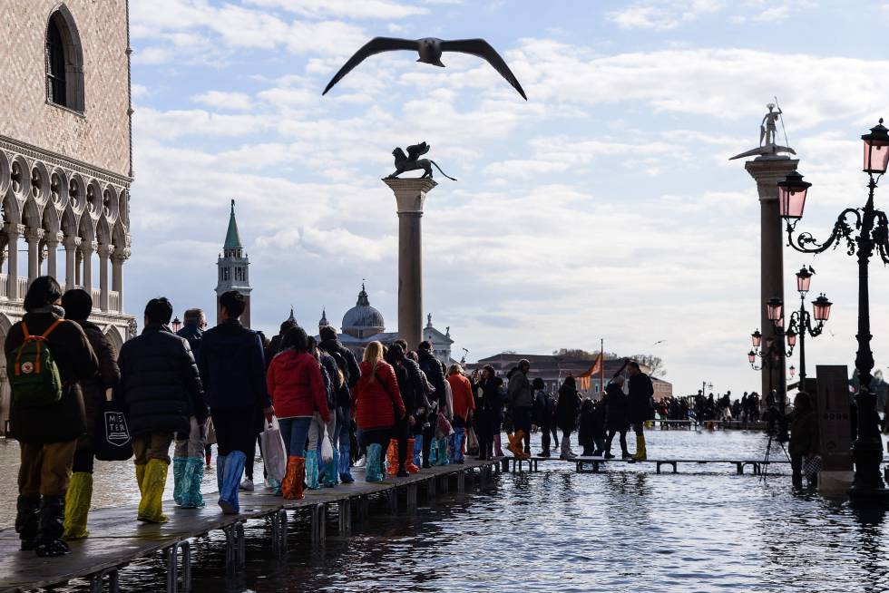 Varias personas caminan por la plaza de San Marcos de Venecia, completamente inundada.