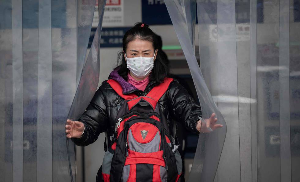 Una mujer de nacionalidad china con una mascarilla en la estación de tren de Beijing.