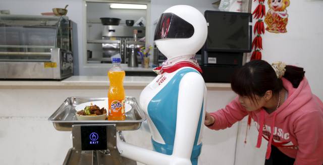 Una mujer introduce las instrucciones en un robot camarera en China.