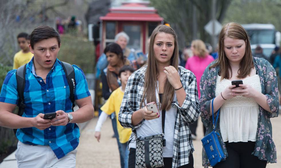 Varios viandantes pasean por una calle de Washington mirando sus teléfonos inteligentes.