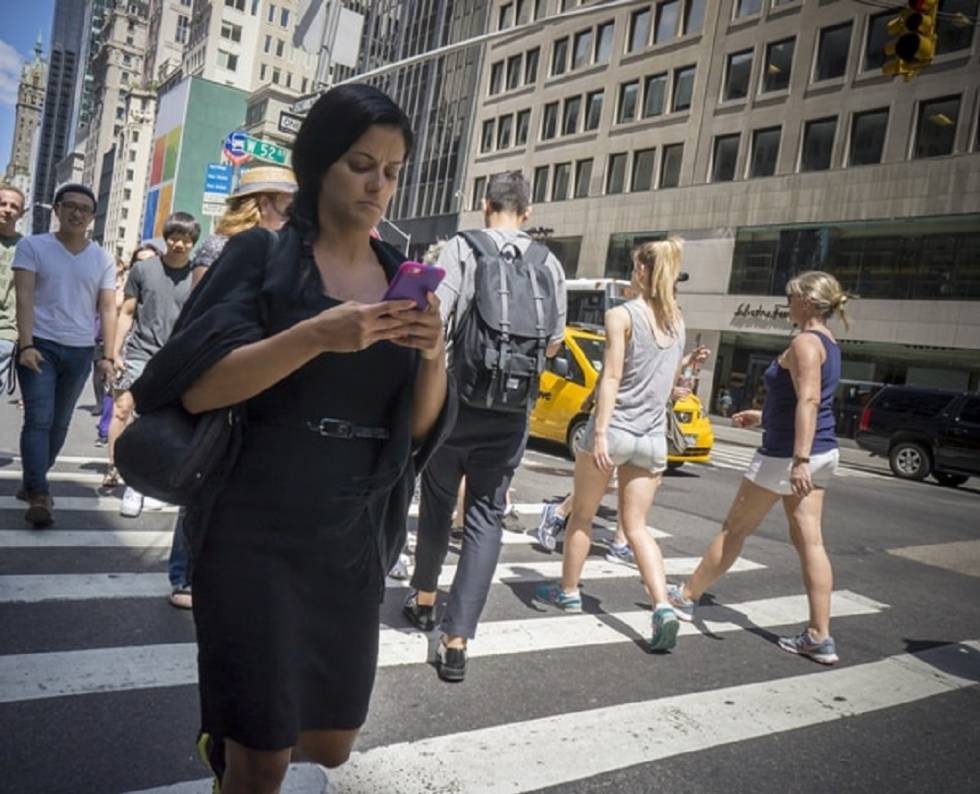 Una mujer mira el móvil mientras cruza la Quinta avenida de Nueva York.