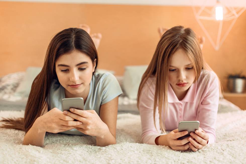 Dos chicas utilizan sus teléfonos móviles. 