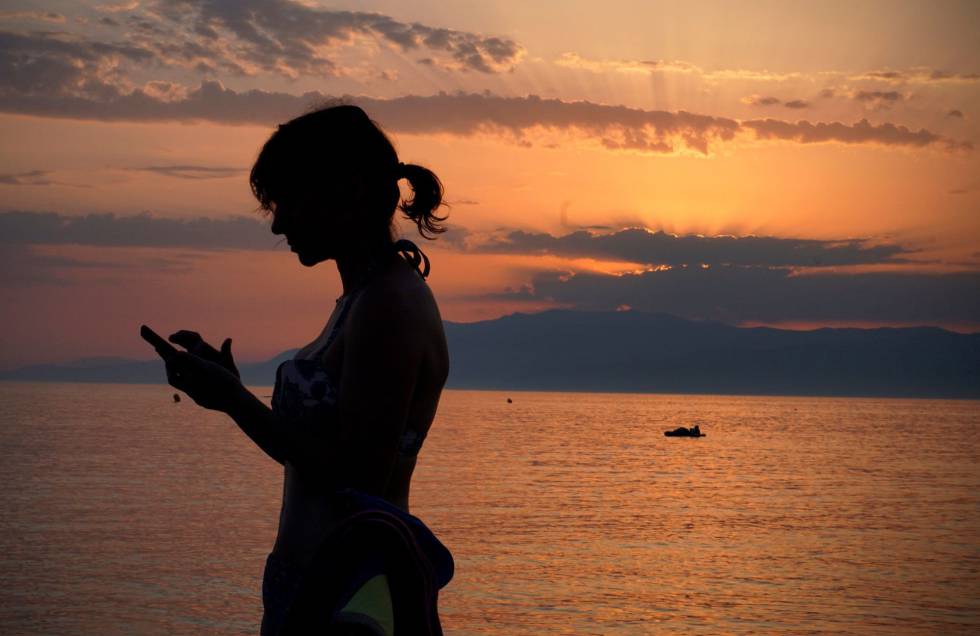 Una mujer revisa su telÃ©fono mÃ³vil en la playa de Cabo de Gata en AlmerÃ­a, este verano.