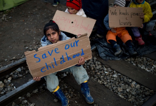 "Salvad nuestra infancia" dice el cartel de esta niña acogida en Idomeni