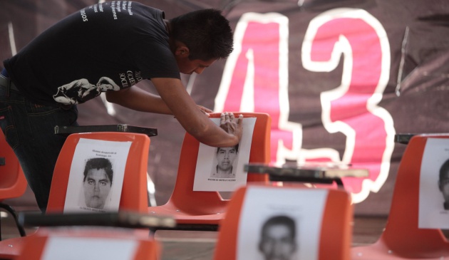 Un alumno de la escuela normal rural "Raúl Isidro Burgos" coloca la fotografía de uno de los 43 estudiantes mexicanos desaparecidos sobre una silla vacía