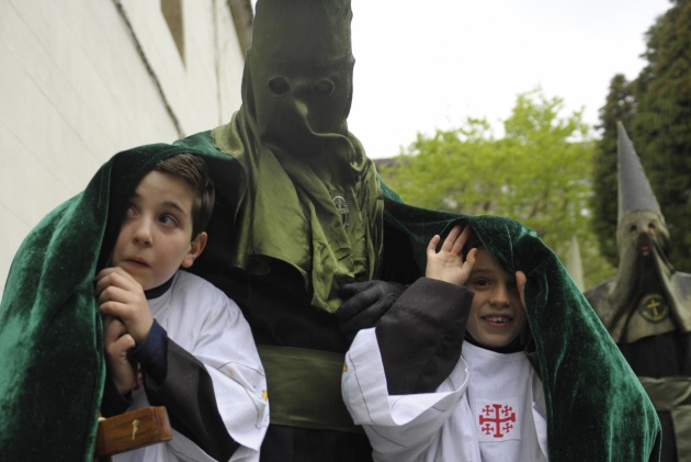 Un penitente protege a dos niños de la lluvia en Santiago de Compostela