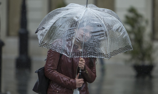 Una mujer se protegen del viento y la lluvia en Sevilla