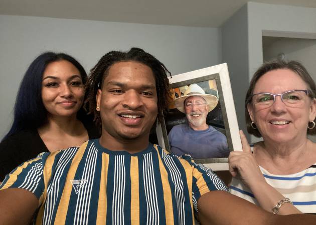 Mikaela Grubbs, Jamal Hinton y Wanda Dench, quien sujeta una foto de su marido fallecido, Lonnie Dench